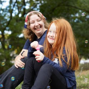 A young girl and an adult volunteer laughing together.