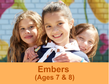 Three Girl Guides aged 7 and 8 hugging and smiling at the camera in front of a floral mural